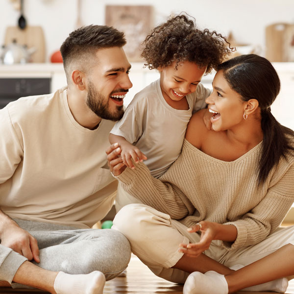 multi-ethnic family laughing while sitting on the floor